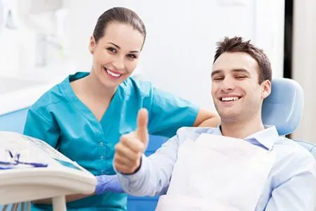 smiling man in dental chair giving a thumbs up